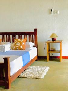 a bedroom with a bed and a table with a lamp at Great Lake Villa in Tissamaharama
