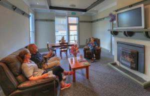 a group of people sitting in a living room with a fireplace at The Dannebrog Lodge in Devonport
