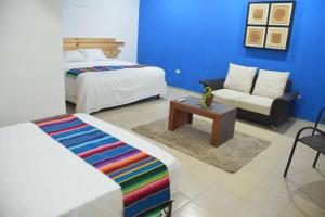 a bedroom with two beds and a couch and a chair at Hostal Casa Bohemia in Mérida