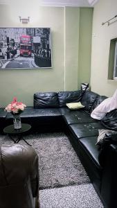 un sofá de cuero negro en una sala de estar con un autobús rojo en The Gulch Apartments en Bonabéri