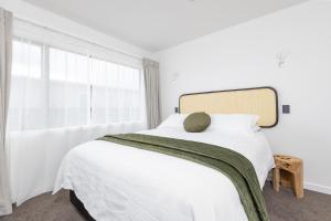 a white bedroom with a bed with a pillow on it at The Green House - Luxury Eco Escape in Martinborough  +27 photos