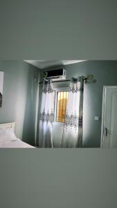 1 dormitorio con 1 cama y una ventana con cortinas en The Gulch Apartments en Bonabéri