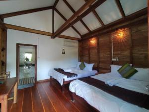 a bedroom with two beds in a room with wooden floors at The Hidden Oasis Bungalows in Kampot