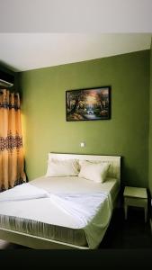 1 dormitorio con 1 cama con pared verde en The Gulch Apartments en Bonabéri