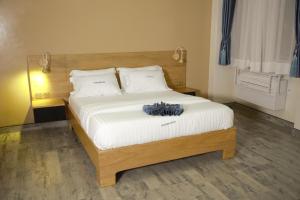1 dormitorio con 1 cama grande con sábanas blancas en Victoria Mews Hotel, en Kampala