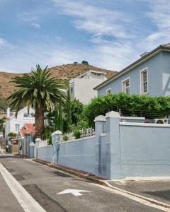 a house with a blue fence and a palm tree at Harpers House in Cape Town
