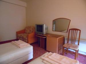 a small room with a bed and a tv and a chair at Hotel Amigos in Obzor