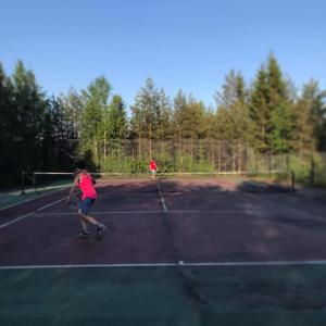 dos personas jugando al tenis en una pista de tenis en Charmig stuga på bondgård en Norrfjärden