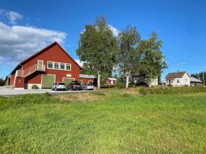 a large red barn with cars parked in a field at Charmig stuga på bondgård in Norrfjärden