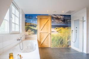 a bathroom with a door leading to a bath tub and a window at Nieuw Leven Texel in Den Burg
