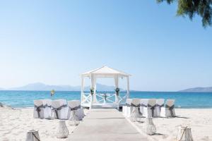 a boardwalk with chairs and a gazebo on the beach at E-GEO Easy Living Resort in Marmari