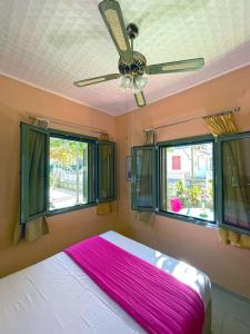 a bedroom with a ceiling fan and two windows at Villa Simotas 4 Four in Póros Kefalonias