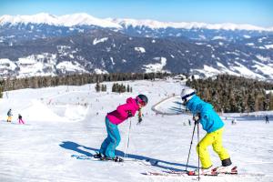 duas pessoas em esquis na neve numa pista de esqui em Panorama Apartment Bauernhof Mandl em Murau