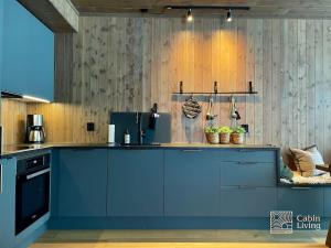 a kitchen with a blue island in a room at New ski in-out apartment with sauna in Hafjell in Øyer +33 photos