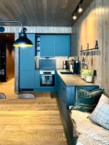 a kitchen with blue cabinets and a couch at Brand new Chalet-apart slope Hafjell Mosetertoppen in Øyer