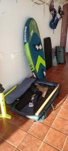 a surfboard sitting on top of a suitcase on the floor at Habitación privada Tenefe in Vecindario