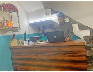 a man sitting at a counter with a laptop at Smart Guest House, Panipat in Pānīpat