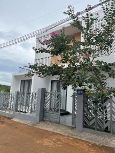 une maison blanche avec des fleurs roses sur elle dans l'établissement Thông Villa, à B'su M'rac