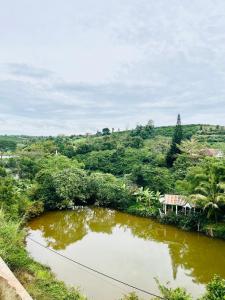 un étang au milieu d'une rivière avec une maison dans l'établissement Thông Villa, à B'su M'rac