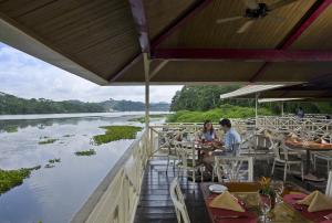 two people sitting at a restaurant next to a river at Gamboa Rainforest Reserve in Gamboa