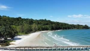 a beach with two people standing on a pier at Bunnan Bungalows and Restaurant in Koh Rong Island