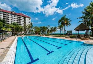 - une piscine dans un complexe avec l'océan en arrière-plan dans l'établissement Glory beach seaview resort 2 bedroom, à Port Dickson