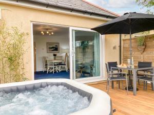 a hot tub on a patio with a table and an umbrella at Little Honeynook in Kingsbridge