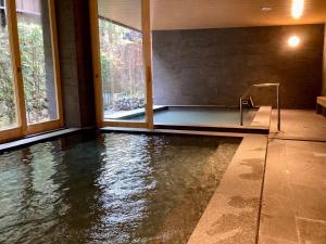 a swimming pool with water in a room with windows at Urakusatsu TOU in Kusatsu