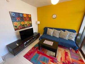 uma sala de estar com um sofá azul e uma televisão em Cozy Central Place renovated 2022 em Sófia