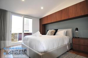 sypialnia z dużym łóżkiem i oknem w obiekcie Squatters Run 6 w mieście Thredbo