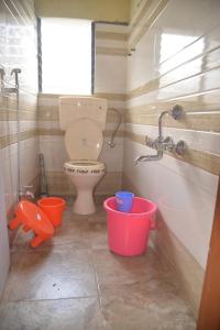 a bathroom with a toilet and buckets in it at Swapnpurti yatri niwas in Kolhapur