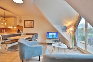 sala de estar con mesa, sillas y TV en Strandduene Stranddüne Appartement 23, en Haffkrug