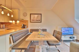 cocina y comedor con mesa de madera y sillas en Strandduene Stranddüne Appartement 23, en Haffkrug
