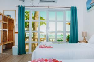 una camera da letto con un letto bianco con tende blu e una grande finestra di johandive a Daanbantayan