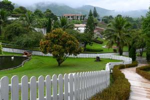 una cerca blanca frente a un patio con un árbol en Swiss Valley Hip Resort, en Suan Phueng