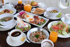 a table topped with plates of food and cups of coffee at Swiss Valley Hip Resort in Suan Phung