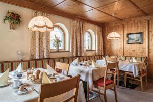 uma sala de jantar com mesas, cadeiras e janelas em Haus Hochland em Tux