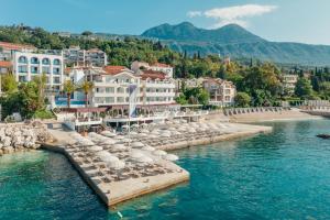 eine Gruppe von Sonnenschirmen und Stühlen im Wasser eines Resorts in der Unterkunft Hotel Perla in Herceg-Novi