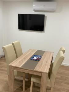 a wooden table with chairs and a television on a wall at Apartmani Daisy in Velika Gorica