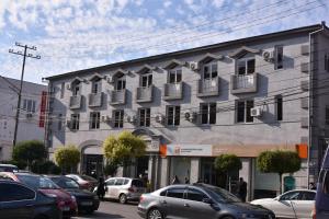 een groot gebouw met auto's geparkeerd op een parkeerplaats bij HOTEL SAMEGRELO in Zugdidi
