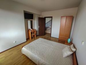een slaapkamer met een bed en een houten vloer bij Къща за гости Даниела in Lozenets