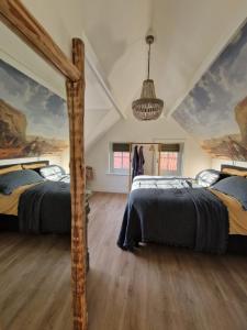 two beds in a room with paintings on the walls at Bed & Breakfast Hoeve Happiness in Voorthuizen