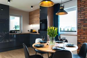 a kitchen and dining room with a wooden table and chairs at Family Resort Ustka - Domki dwupoziomowe z basenem in Ustka