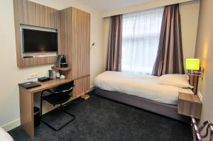 アムステルダムにあるHotel Fine Harmonyのベッド、デスク、テレビが備わるホテルルームです。