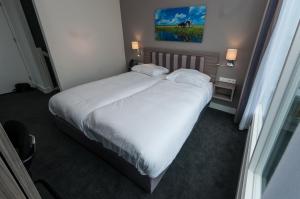 a bedroom with a large white bed with two pillows at Hotel Fine Harmony in Amsterdam