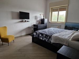 a bedroom with a bed and a tv and a chair at La casa di Andrea in Messina