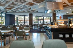 een restaurant met tafels en stoelen en een chef-kok die maaltijden bereidt bij Astral Village Hotel in Eilat