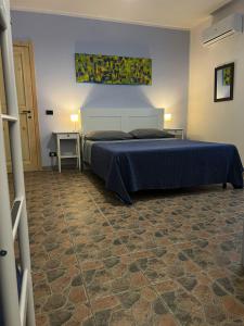 a bedroom with a bed with a blue bedspread and a table at Agriturismo Graziano e Barbara in Porto Conte
