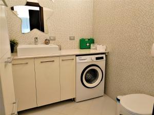 een badkamer met een wasmachine en een wastafel bij Bareggio Comfort Apartment in Bareggio