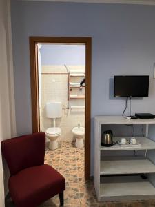 a room with a toilet and a chair and a television at Agriturismo Graziano e Barbara in Porto Conte